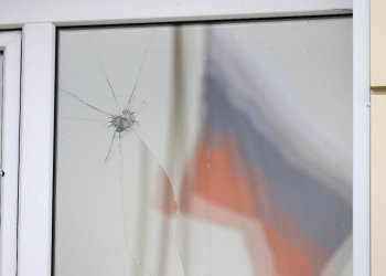 A Russian flag reflected in a damaged window after an aerial attack near Belgorod on Tuesday / ©AFP
