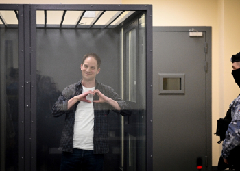 US journalist Evan Gershkovich, arrested on espionage charges, shapes a heart with his hands inside a defendants' cage in a Moscow court / ©AFP