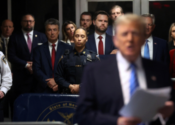 Senator JD Vance (center, red tie), Senator Tommy Tuberville (back right, blue tie) and Eric Trump (center back) look on as former US president Donald Trump speaks to reporters at his trial for allegedly covering up hush money payments / ©AFP