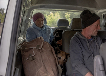 Evacuees from villages in Ukraine's Kharkiv region wait in a car at a checkpoint / ©AFP
